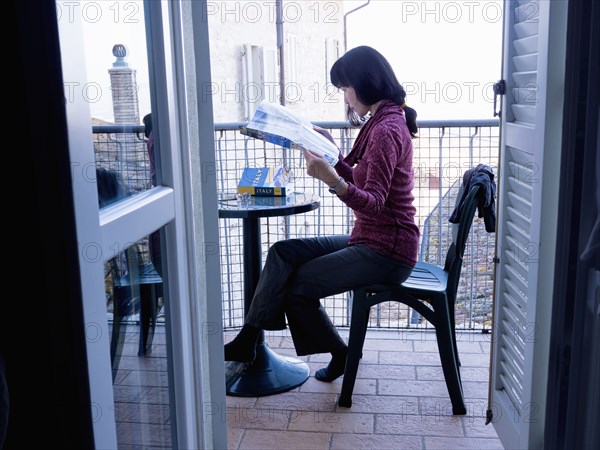 Japanese woman reading map on balcony