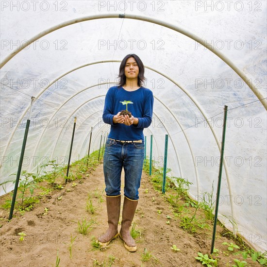 Japanese gardener holding potted plant in greenhouse