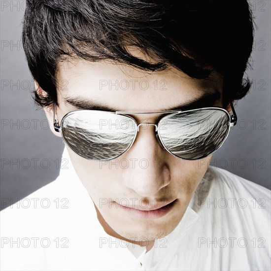 Mixed race man in sunglasses reflecting water