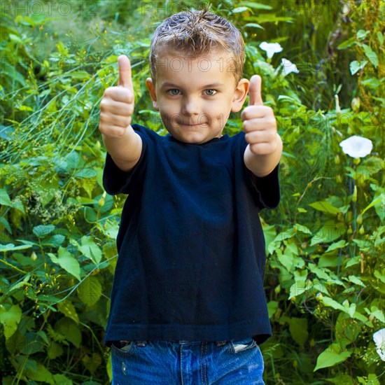 Caucasian boy giving thumbs up in garden