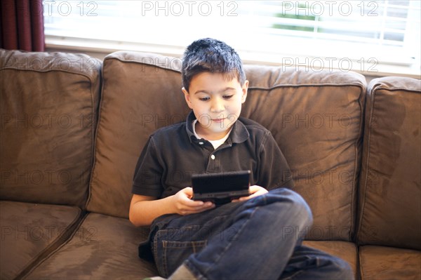 Mixed race teenage boy playing video games on sofa