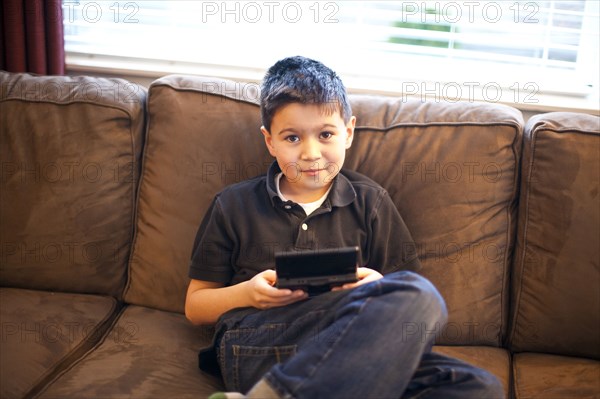 Mixed race teenage boy playing video games on sofa