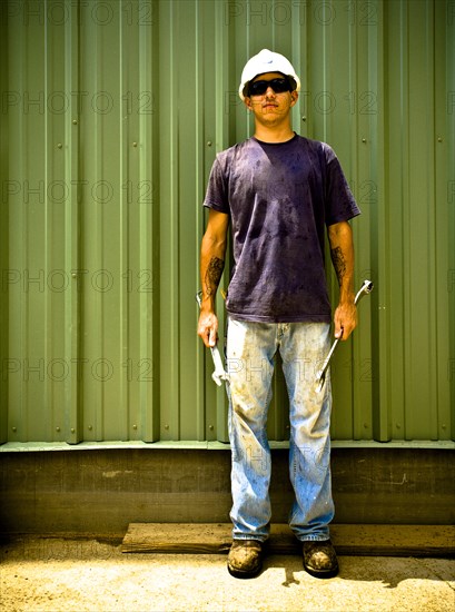 Caucasian construction worker holding wrenches on work site