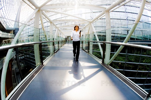 Japanese woman walking on footbridge texting on cell phone