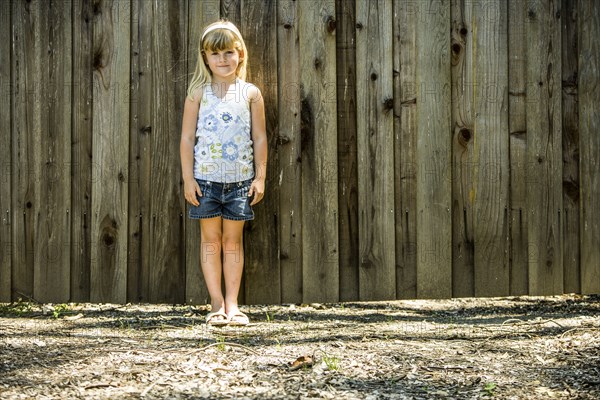 Caucasian girl standing at wooden fence