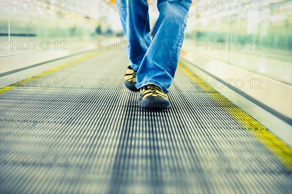 Legs of Japanese woman wearing jeans walking on moving walkway