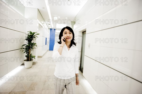 Japanese businesswoman talking on cell phone in corridor