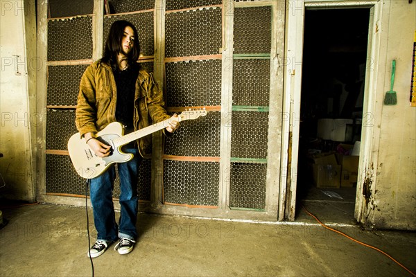 Mixed Race man playing electric guitar outdoors