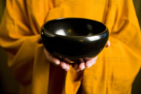 Monk in orange robe holding black bowl