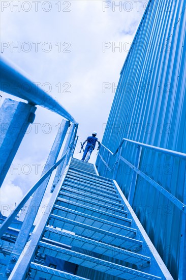 Blue collar worker at top of industrial staircase