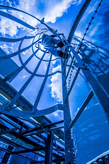 Caucasian man climbing ladder on storage tank