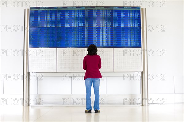 Japanese woman reading departure schedules at airport