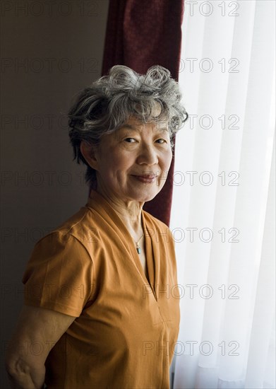 Smiling Japanese woman standing at window