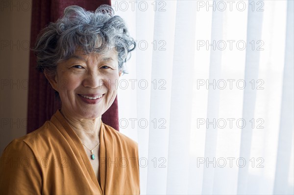 Smiling Japanese woman standing at window