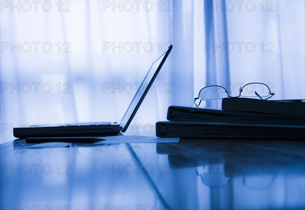 Eyeglasses and laptop near window curtains