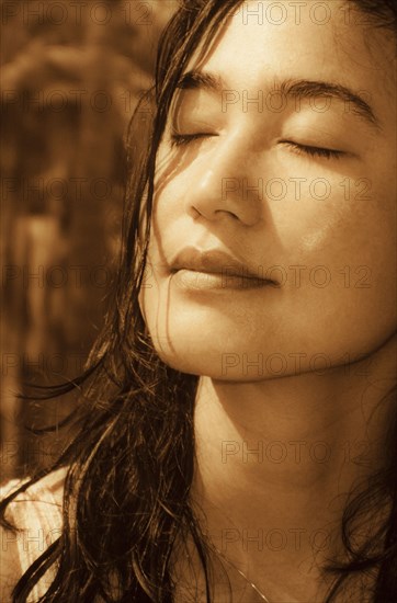 Japanese woman with eyes closed on sunny day