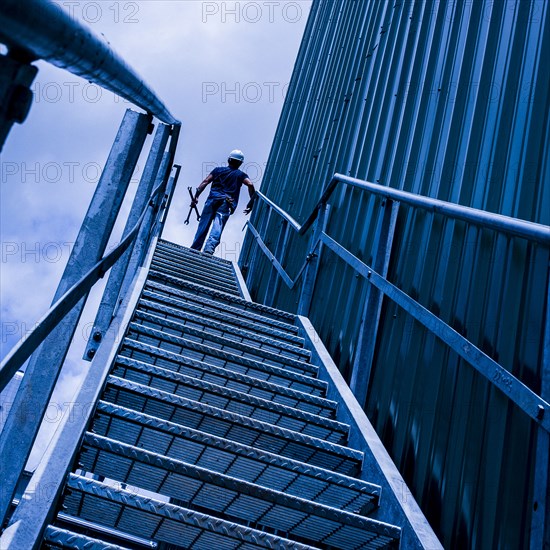 Caucasian worker carrying tools on staircase
