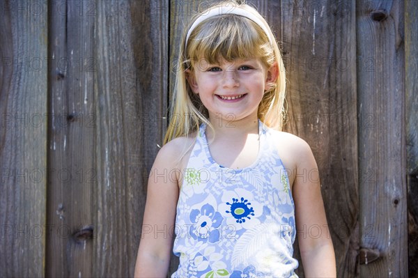 Smiling Caucasian girl posing at wooden fence