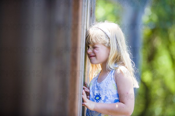Curious Caucasian girl peeking through wooden fence