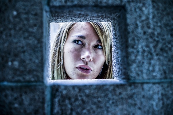 Curious Mixed Race woman looking through stone wall