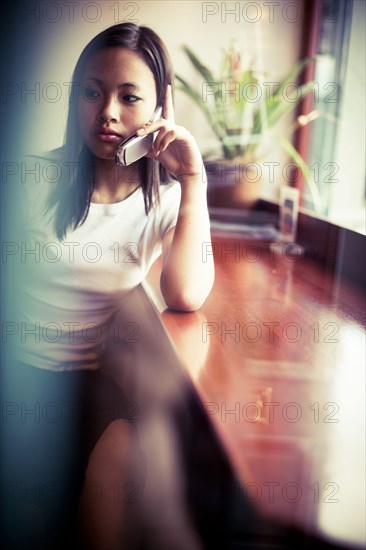 Serious Asian girl talking on cell phone