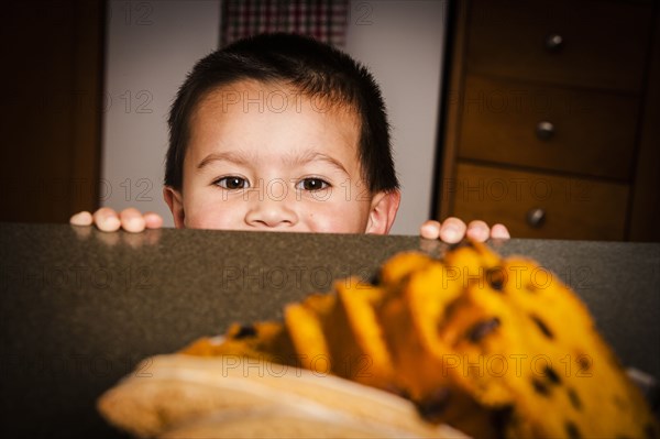 Mixed Race boy looking at cake on counter