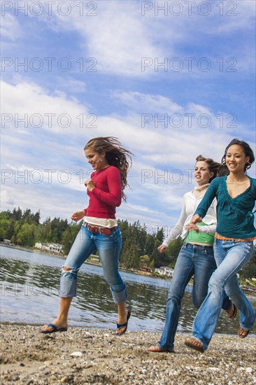 Smiling girls running on rocky beach