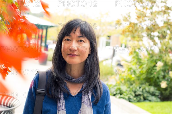 Japanese woman smiling near autumn leaves