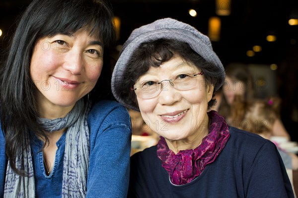 Older Japanese mother and daughter smiling in restaurant