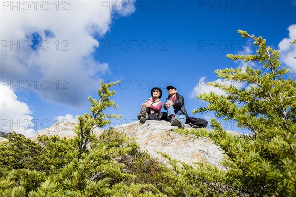 Older Japanese mother and daughter sitting on rock