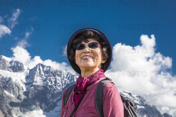 Older Japanese woman smiling near mountain