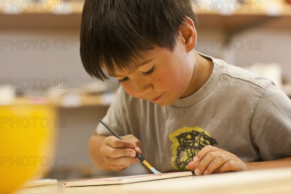 Mixed Race boy painting in art class