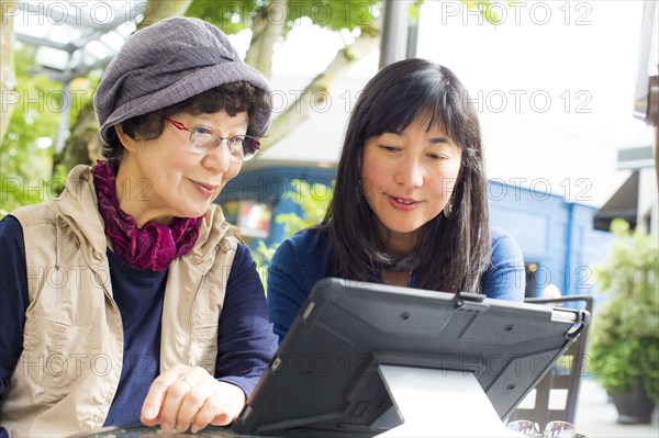 Older Japanese mother and daughter using digital tablet