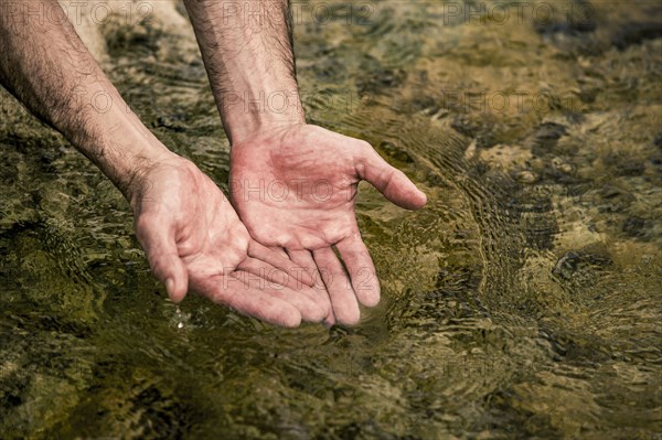 Hands of man cupping water