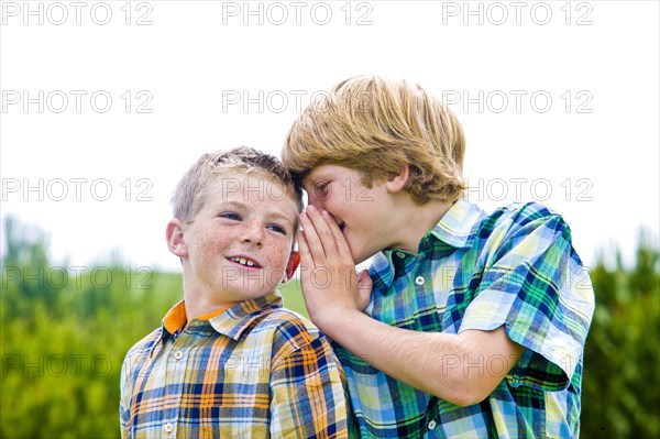 Caucasian boy whispering to brother