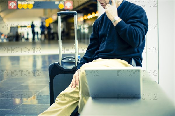 Caucasian man talking on cell phone at airport
