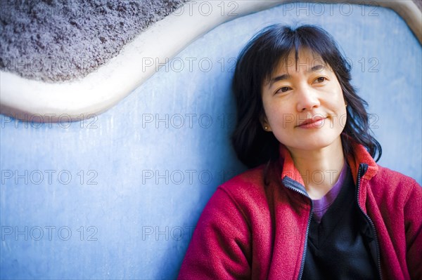 Pensive Japanese woman leaning on wall