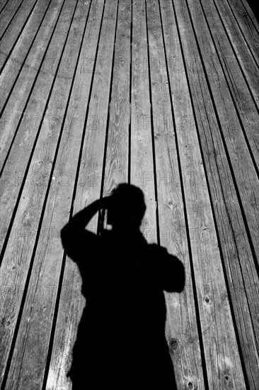 Shadow of Caucasian man with camera on wooden floor