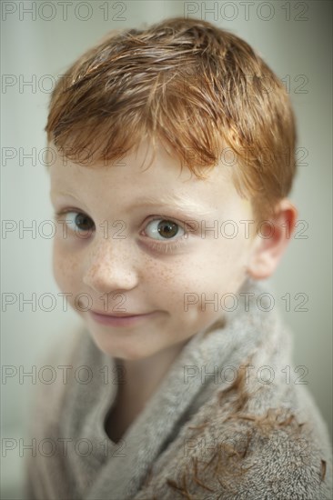 Caucasian boy wrapped in towel after haircut