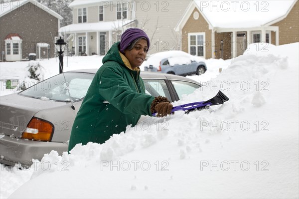 African American woman scraping snow from windshield