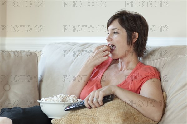 Caucasian woman eating popcorn and watching television