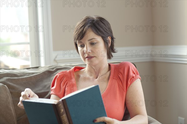 Caucasian woman on sofa reading book