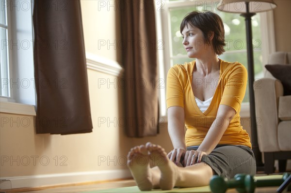 Caucasian woman sitting on exercise mat