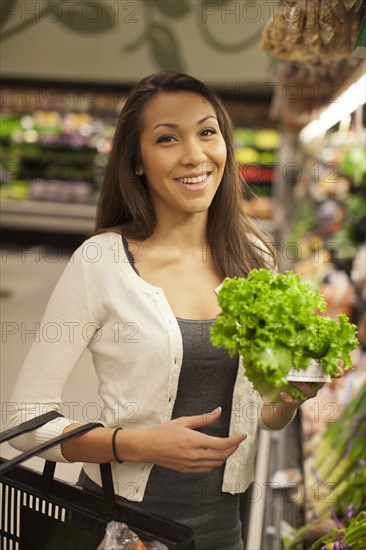 Mixed race woman buying produce in supermarket