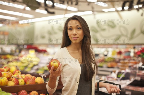 Mixed race woman buying produce in supermarket