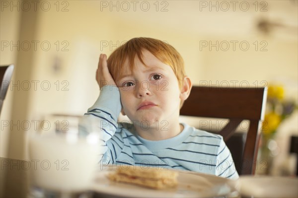 Caucasian boy pouting at dinner table