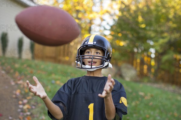 Mixed race boy playing football outdoors