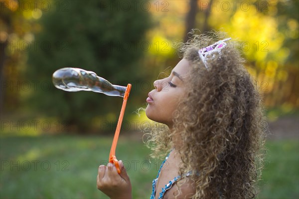 Mixed race girl blowing bubbles outdoors