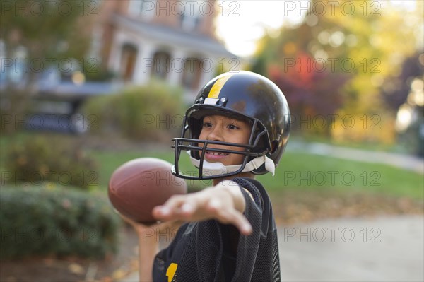 Mixed race boy playing football outdoors