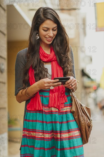 Mixed race woman using cell phone on city street